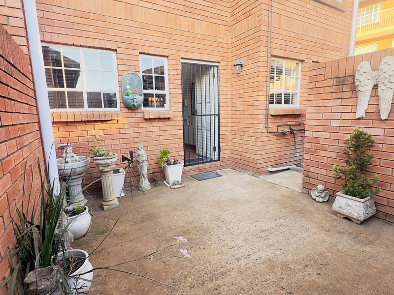 A private rear courtyard featuring exposed brick walls, a concrete patio area, and secure access to the apartment interior.