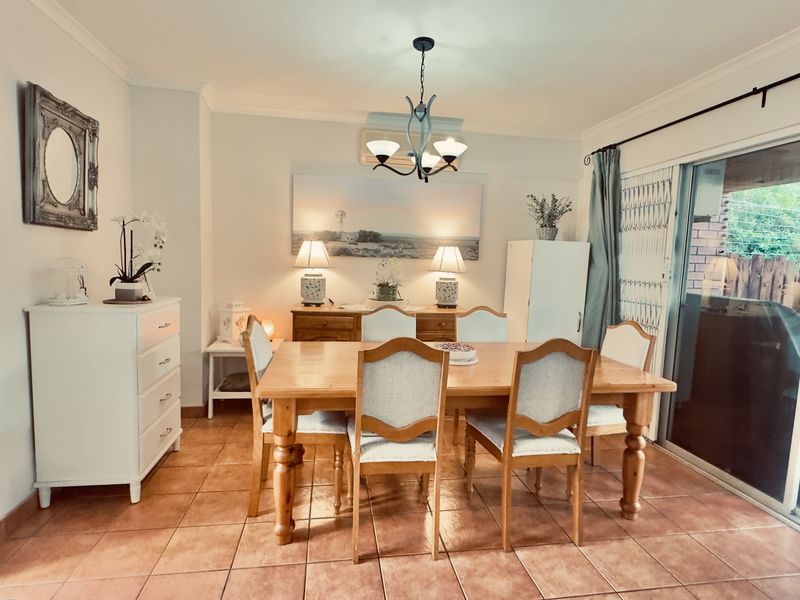 A well-lit dining room featuring tiled flooring, a ceiling light fixture, and large sliding glass doors providing access to the outdoor area.
