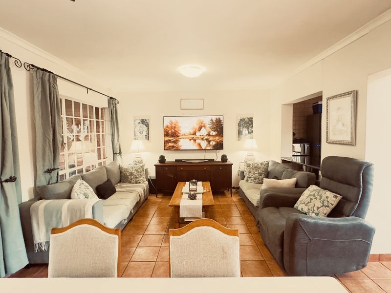 A comfortable living room featuring tiled flooring, a large sliding glass door providing natural light, and neutral wall finishes.