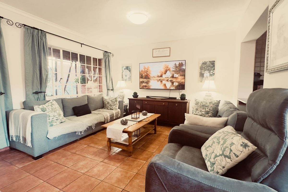 A comfortable living room featuring tiled flooring, a large window with natural light, and neutral wall finishes.