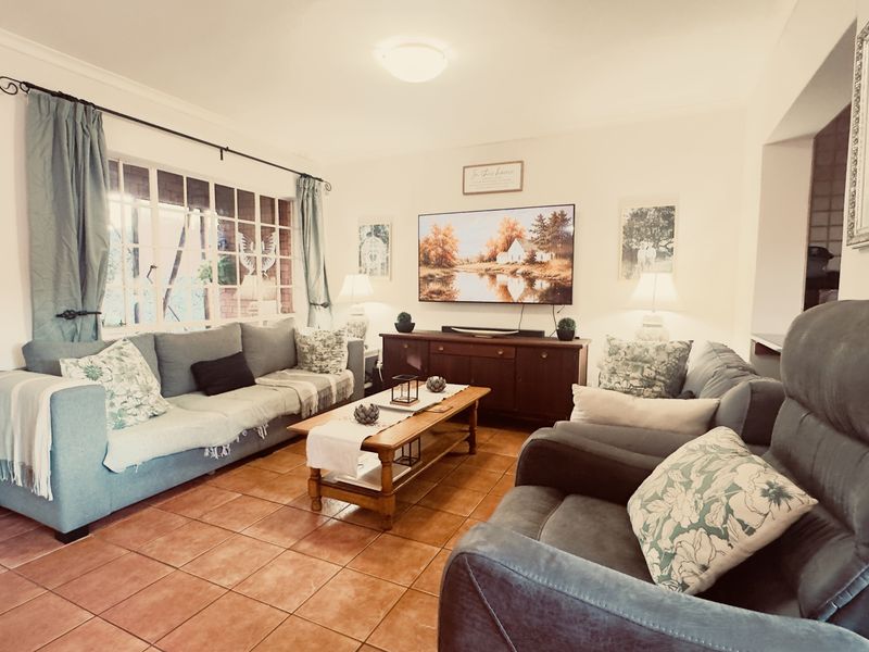 A comfortable living room featuring tiled flooring, a large window with natural light, and neutral wall finishes.