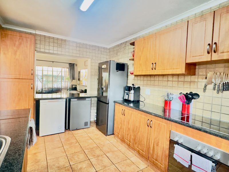 A functional kitchen featuring wooden cabinetry, granite countertops, tiled backsplash, and built-in appliances, offering a practical layout with ample storage space.