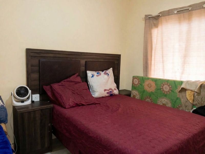A functional bedroom space featuring a neutral wall finish and a window with a curtain rod.