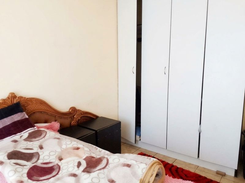 A bedroom featuring a built-in wardrobe with white doors and tiled flooring.