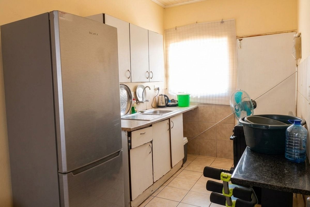 A functional kitchen featuring tiled flooring, granite countertops, and built-in cabinetry, currently showing signs of wear and in need of cosmetic updates.