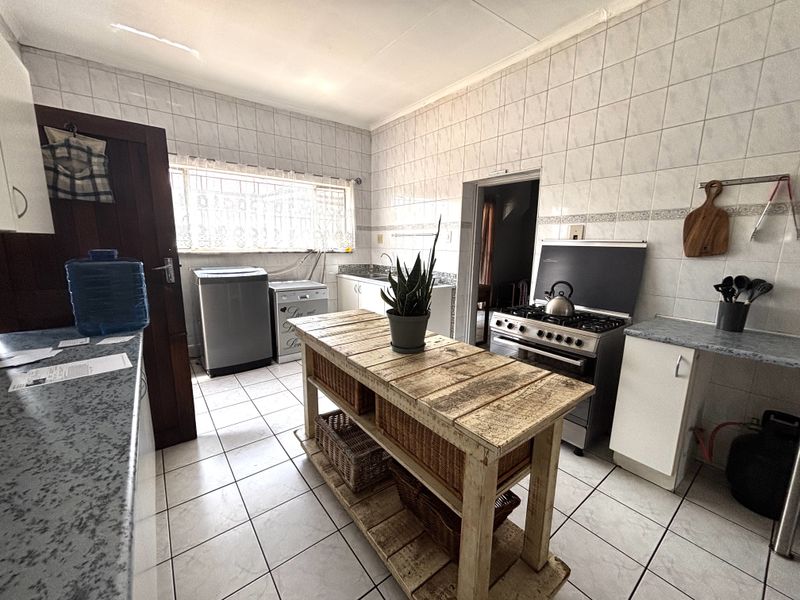Functional kitchen featuring tiled walls and floors, built-in cabinetry, laminate countertops, and a gas stove with extractor hood.