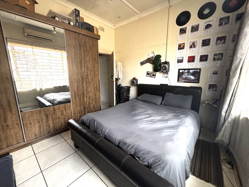 A bedroom featuring tiled flooring, a built-in wardrobe with mirrored doors, and an integrated air conditioning unit.