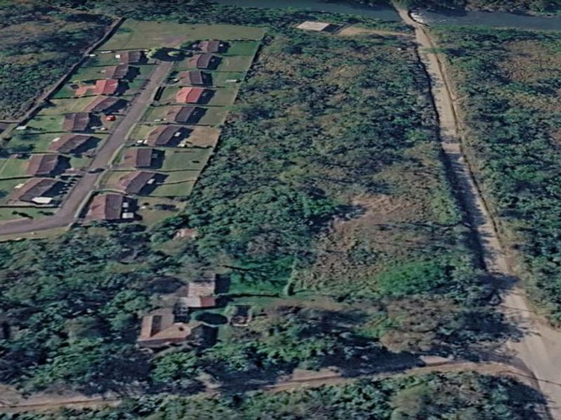 Aerial view of a large, undeveloped residential land parcel featuring dense vegetation and proximity to existing residential housing and local road infrastructure.