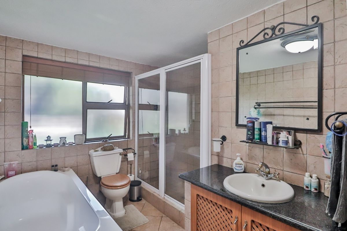 A functional bathroom featuring a bathtub, separate shower enclosure, vanity with granite countertop, and tiled walls.