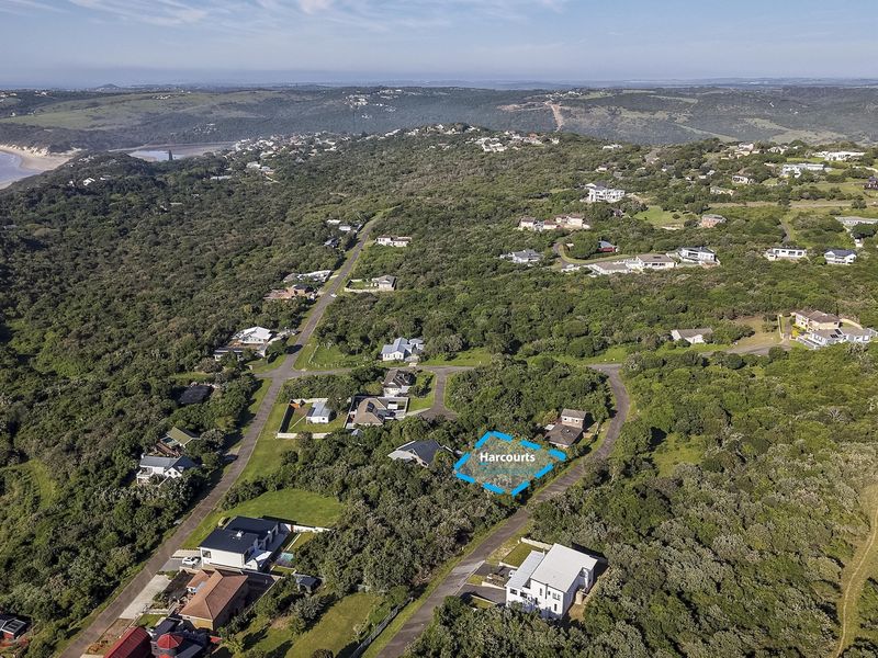 An aerial view of a residential vacant land plot situated within a coastal neighborhood, surrounded by lush vegetation and proximity to the ocean.