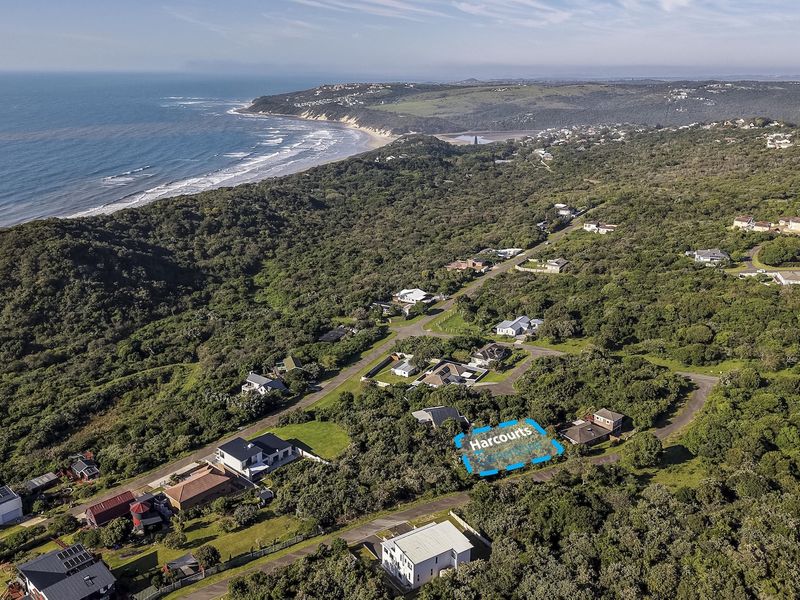 Aerial view of a residential vacant land plot situated in a coastal neighborhood with surrounding natural vegetation and ocean views.
