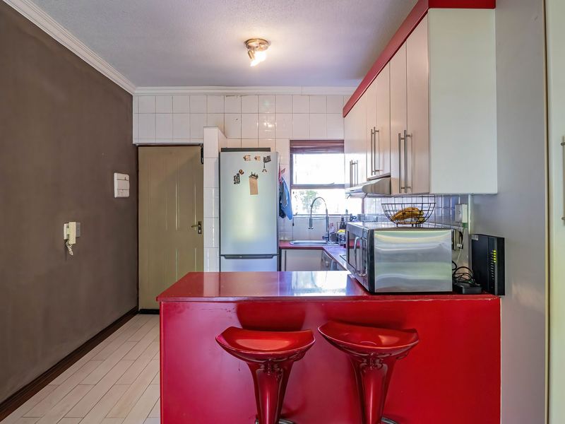 A functional kitchen featuring built-in cabinetry, a tiled backsplash, and a breakfast bar, offering a practical layout for daily meal preparation.