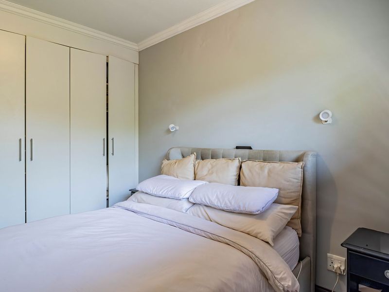 A well-maintained bedroom featuring neutral wall tones, crown molding, and ample built-in cupboard storage space.