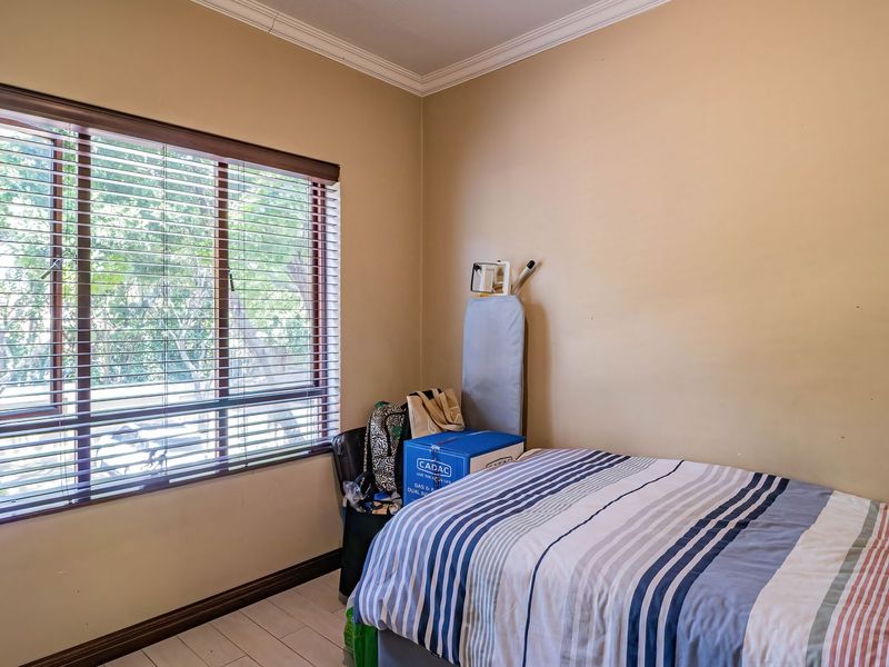 A bedroom featuring neutral walls, coving, skirting boards, and a large window with fitted venetian blinds.