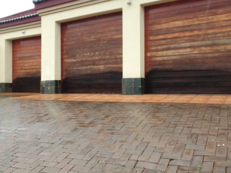 A triple garage featuring timber doors with stone cladding accents and a paved driveway.