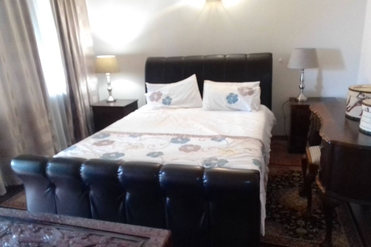 A bedroom featuring a central bed and wall-mounted lighting, providing a functional space for rest.