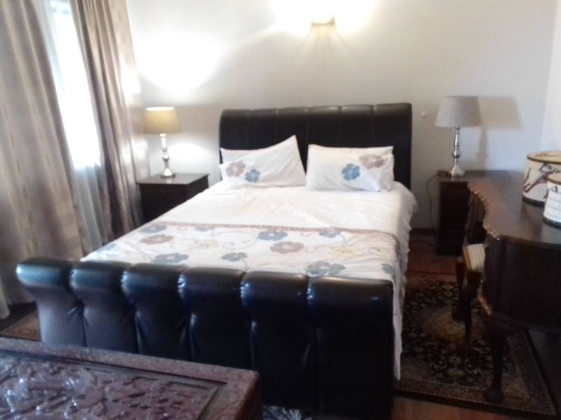 A bedroom featuring a central bed and wall-mounted lighting, providing a functional space for rest.