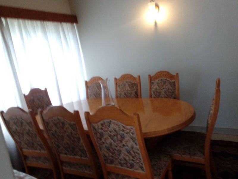A dining room featuring a wall-mounted light fixture and window with curtain rail.