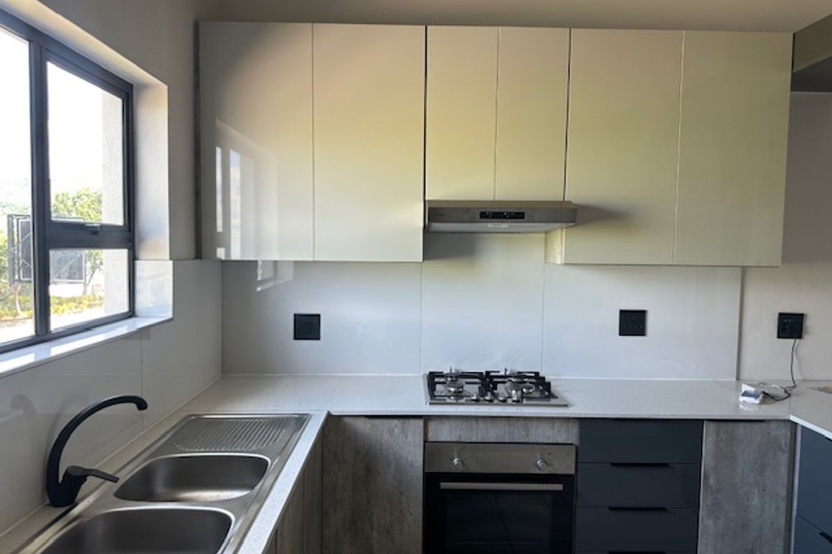 Modern kitchen featuring sleek cabinetry, stone countertops, a gas hob, built-in oven, and a double bowl sink with a contemporary faucet.