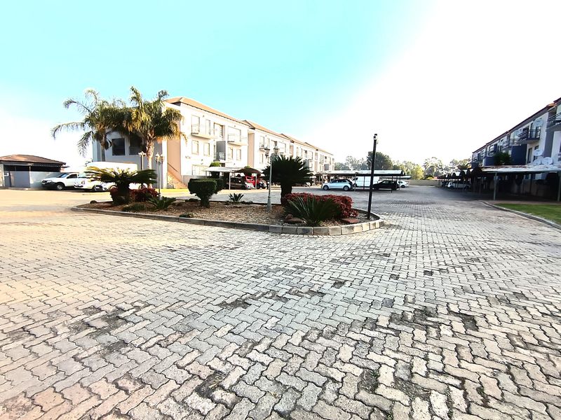 Exterior view of the apartment complex featuring a paved driveway, landscaped garden island, and covered parking facilities for residents.
