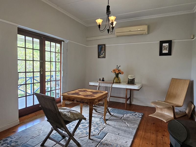 A bright living room featuring polished hardwood floors, a wood-burning fireplace, and direct access to an outdoor patio through classic french doors.