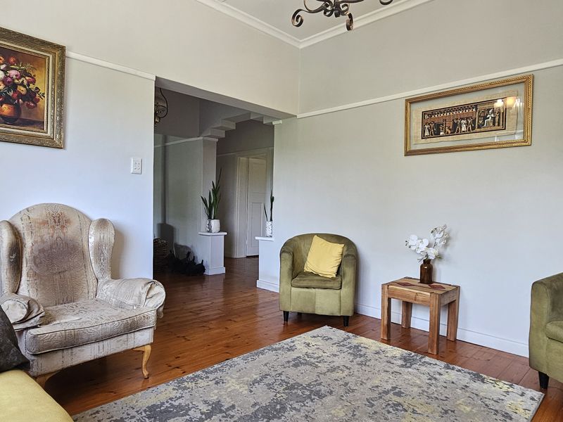 A living room featuring original hardwood flooring, classic picture rails, and an architectural archway leading to an adjacent space.