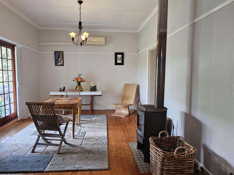 A cozy living room featuring polished hardwood floors, a wood-burning stove, and direct access to the outdoors through classic french doors.