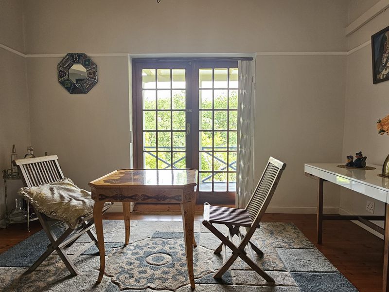 A living area featuring polished hardwood floors, a picture rail, and classic French doors providing natural light and access to the exterior.