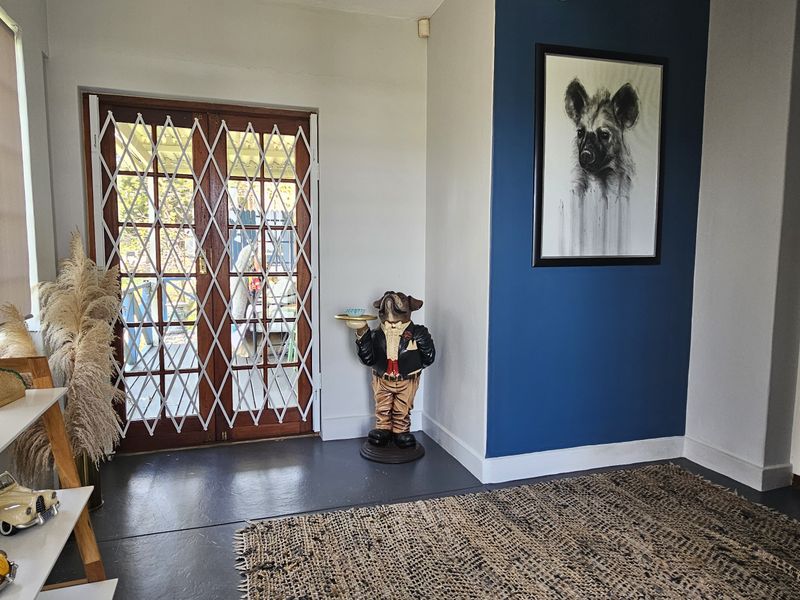 A bright entrance hall featuring painted concrete floors, a bold blue accent wall, and timber-framed glass doors with integrated security gates.