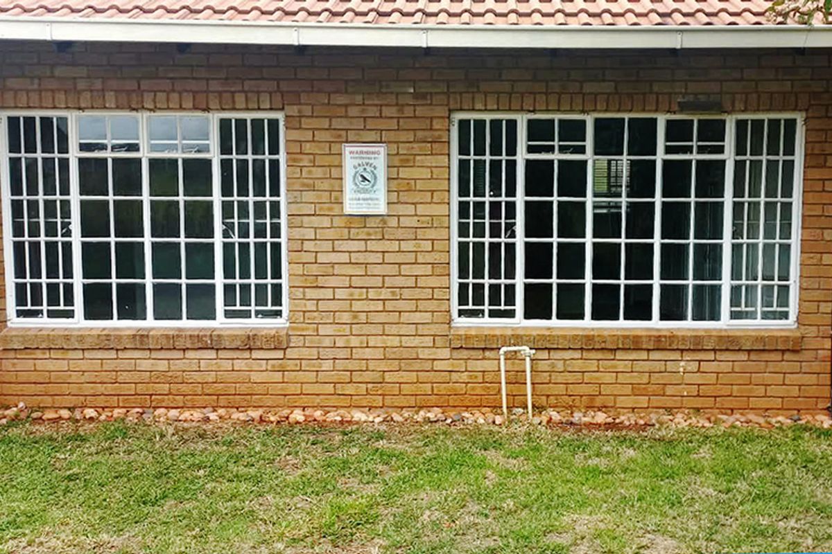 Rear exterior view of the retirement unit featuring face brick walls, security-barred windows, and a tiled roof.