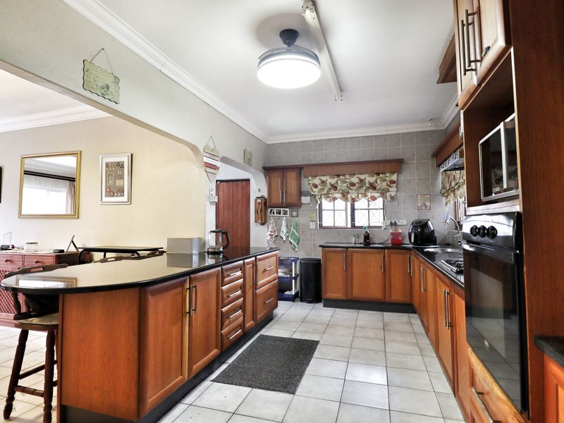 A functional kitchen featuring warm-toned wooden cabinetry, granite countertops, a breakfast bar, and built-in appliances, offering a classic and practical layout.