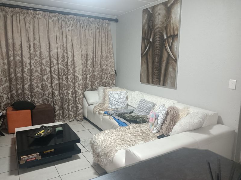 A living room area featuring tiled flooring and a curtain rail, providing a functional space for relaxation.