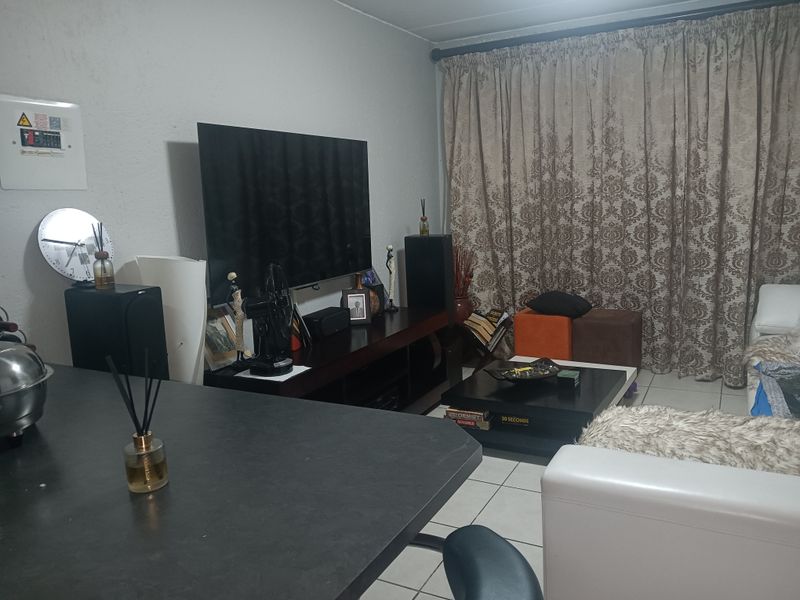 A living room area featuring tiled flooring and a wall-mounted electrical distribution board, providing a functional space for relaxation.
