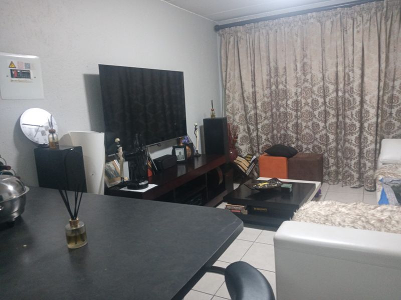 A living room area featuring tiled flooring and a wall-mounted electrical distribution board, providing a functional space for relaxation.