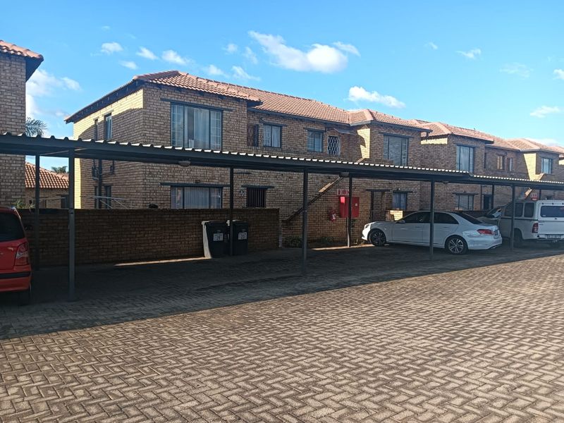 Exterior view of a face brick apartment complex featuring a covered carport area and paved driveway.
