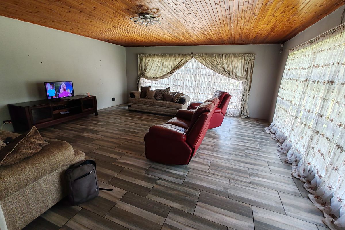 Spacious living room featuring wood-look tiled flooring and a warm timber tongue and groove ceiling, offering a comfortable and inviting atmosphere.