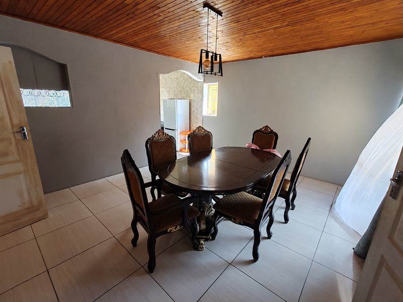 Dining room featuring a timber tongue and groove ceiling, tiled flooring, and an arched entryway leading to the kitchen area.