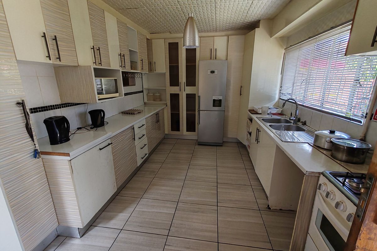 A functional kitchen featuring extensive built-in cabinetry, a double sink, tiled flooring, and a built-in oven with hob, offering a practical layout for daily use.