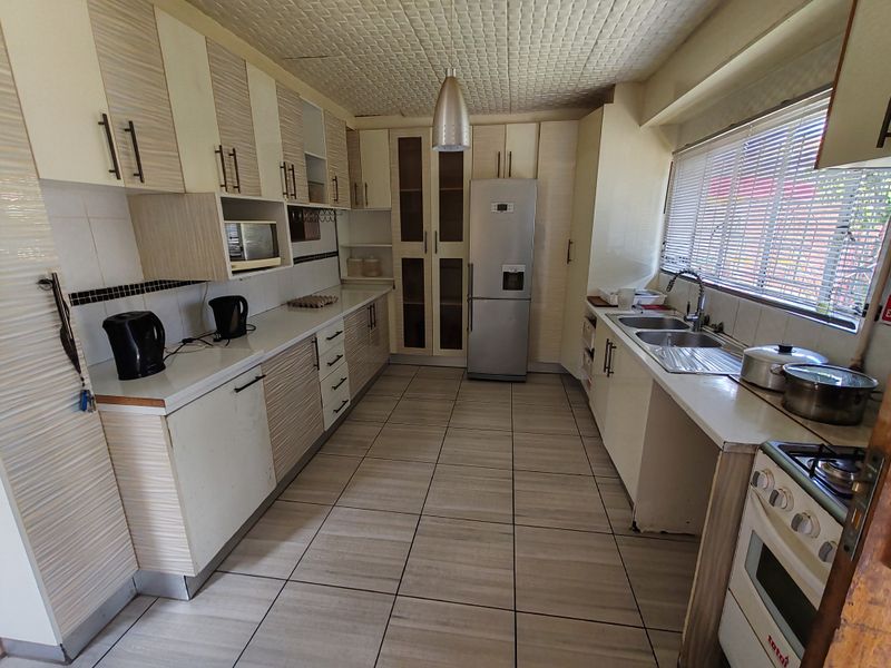 A functional kitchen featuring extensive built-in cabinetry, a double sink, tiled flooring, and a built-in oven with hob, offering a practical layout for daily use.