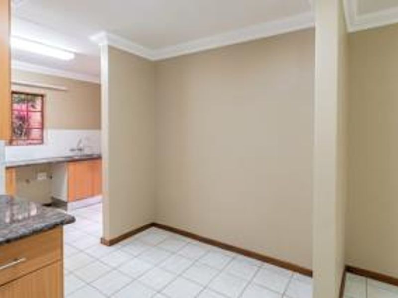 A functional scullery area featuring built-in cabinetry, granite countertops, a sink, and tiled flooring, providing a dedicated space for food preparation and cleanup.