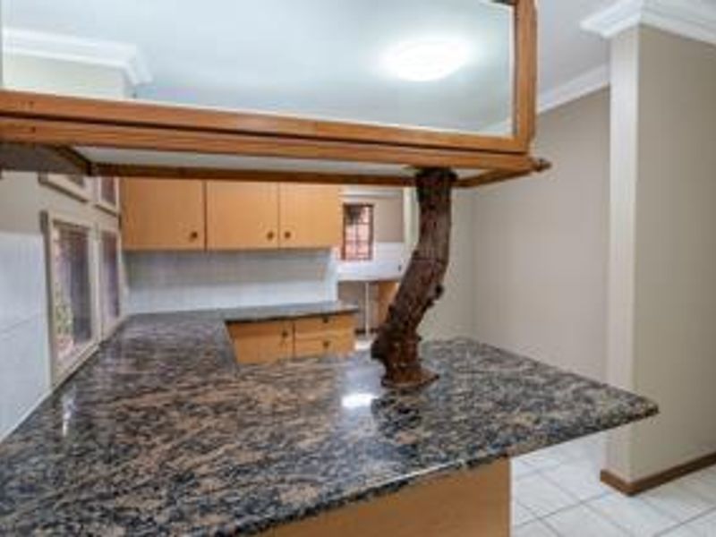 A kitchen area featuring granite countertops, built-in wooden cabinetry, and tiled flooring, offering a functional layout ready for modern updates.