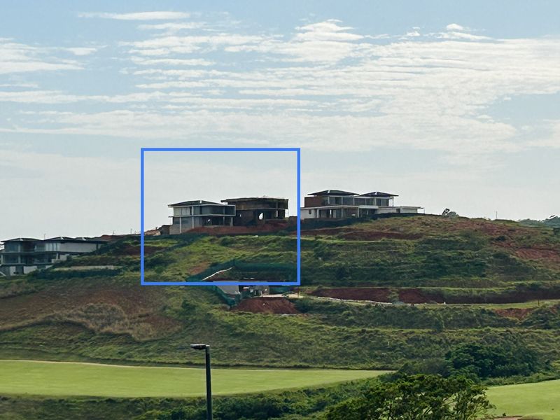 An elevated view of a hillside residential development featuring multiple townhouse structures currently under construction with exposed structural frameworks.