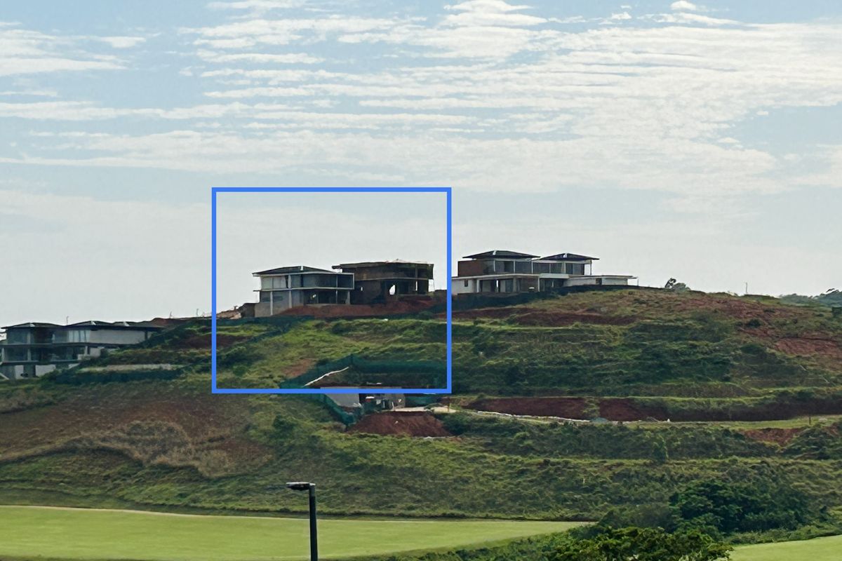 An elevated view of a hillside residential development featuring multiple townhouse structures currently under construction with exposed structural frameworks.