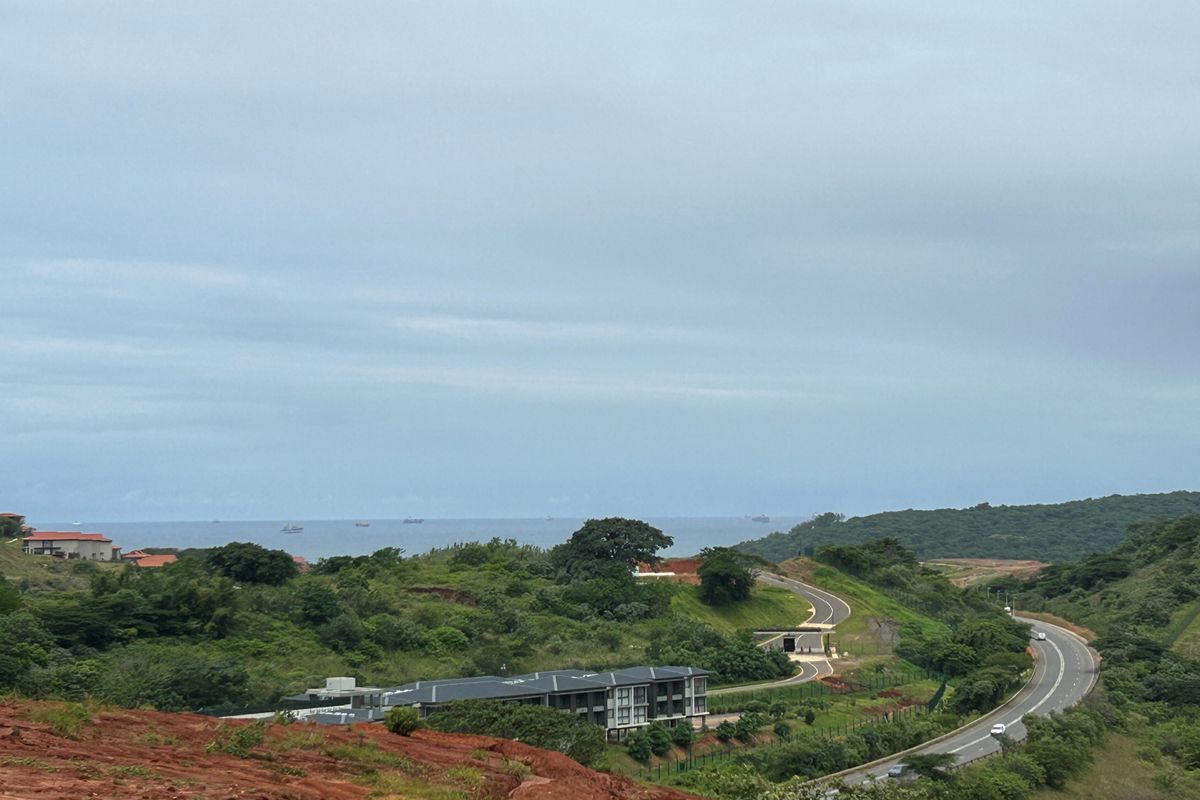 Elevated landscape view overlooking the surrounding estate, winding access roads, and distant ocean horizon.