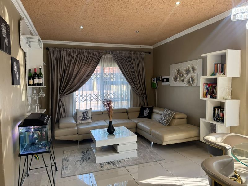 A well-maintained living room featuring tiled flooring, recessed downlighting, and a textured ceiling, providing a comfortable and functional space.