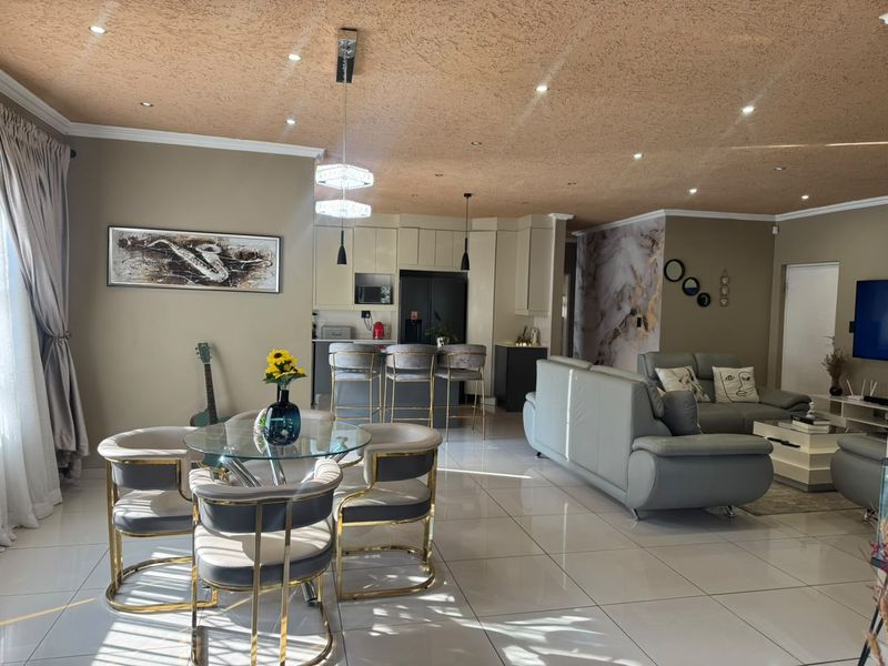 Spacious open-plan living and dining area featuring modern porcelain floor tiles, recessed lighting, and a well-appointed kitchen with a central island.