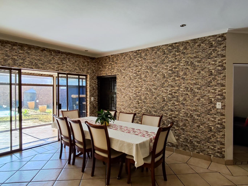 Spacious dining room featuring tiled flooring, a stone-effect feature wall, and large sliding glass doors providing direct access to the outdoor patio area.