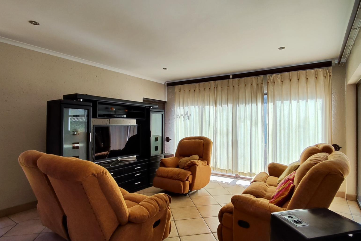 A spacious living room featuring tiled flooring, recessed downlighting, and large sliding glass doors that provide ample natural light and access to the outdoors.