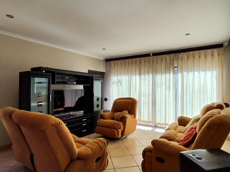 A spacious living room featuring tiled flooring, recessed downlighting, and large sliding glass doors that provide ample natural light and access to the outdoors.