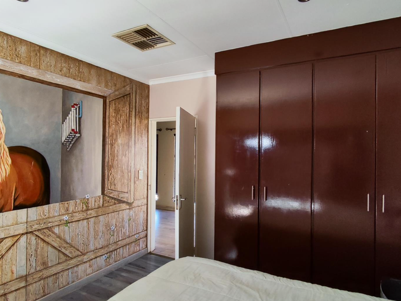 A bedroom featuring dark built-in cupboards and a decorative mural wall, providing ample storage space and a unique aesthetic.